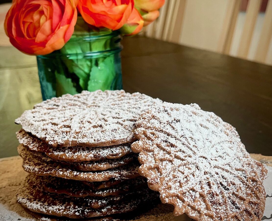 stack of chocolate pizzelle with powdered sugar